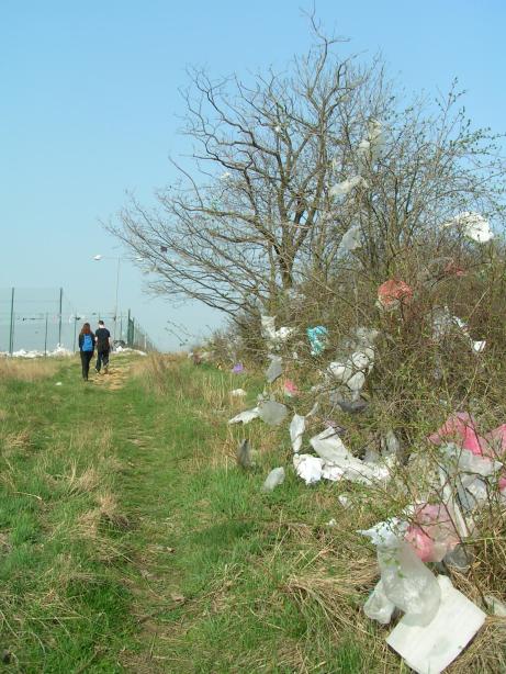 cesta vedla kolem skl�dky, okolo kter� v�ude poletuj� igelitov� s��ky